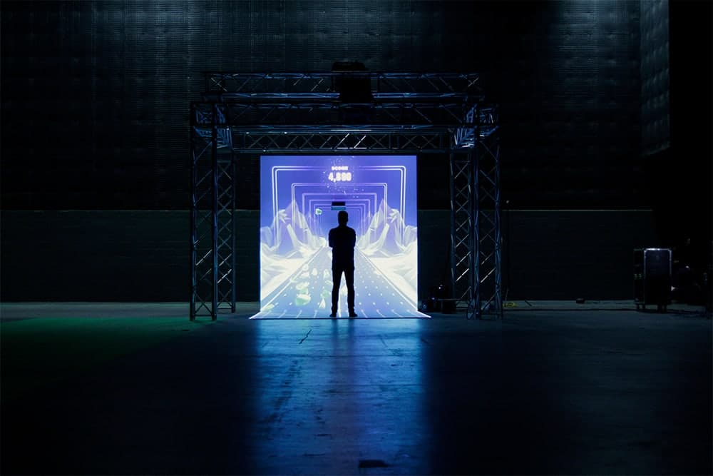 A lone player silhouette standing in front of an ANZ Breakpoint projection booth during installation testing.