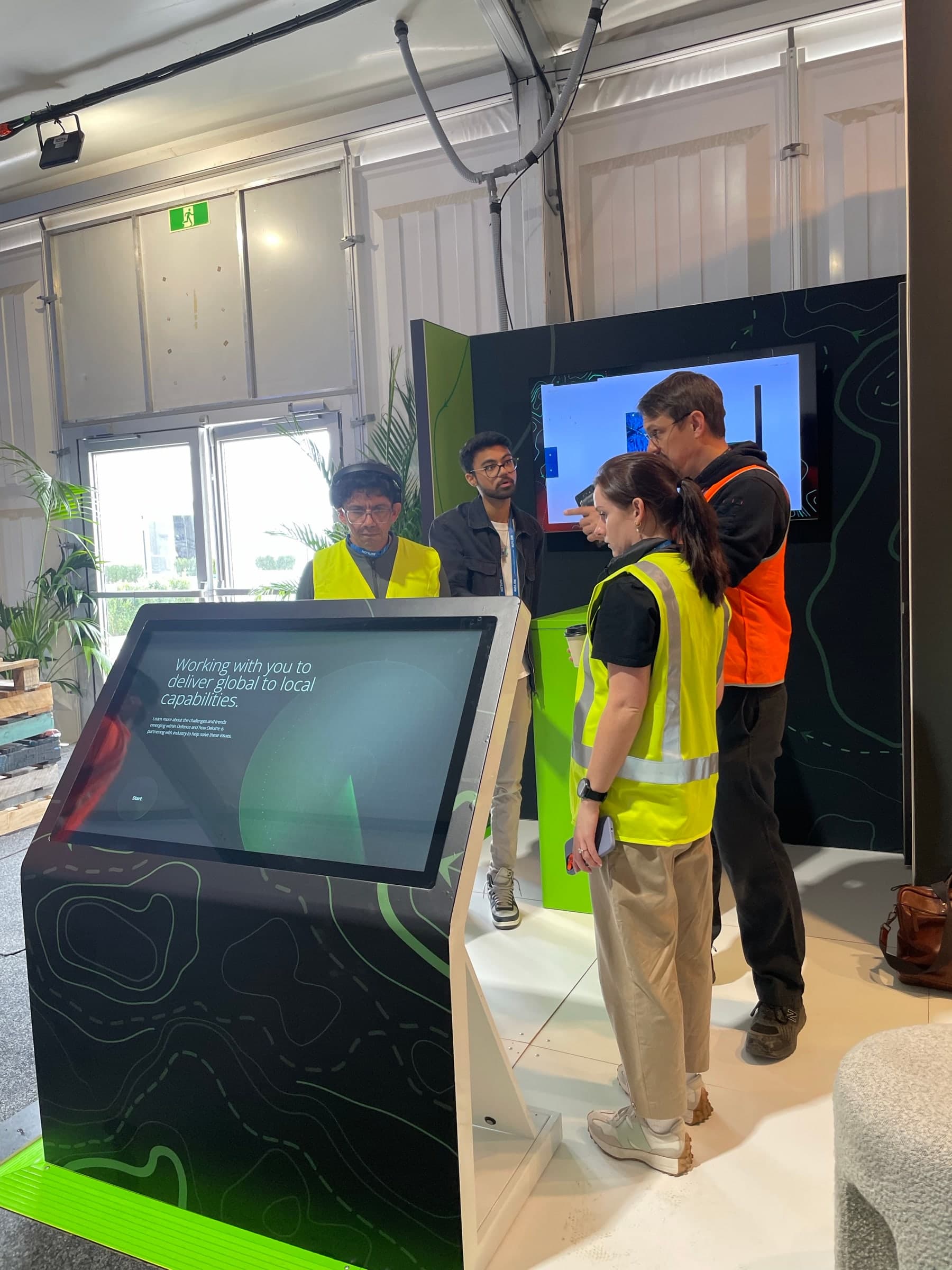 Wider view of the working touchscreen and surrounding Deloitte activation during event setup.